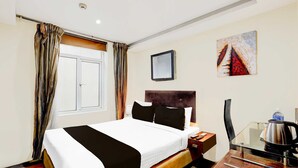Ein Hotelzimmer mit einem Bett, einem Nachttisch mit Wasserkocher, einem Sessel und einem Bild an der Wand.