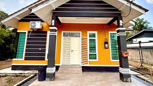 A modern house with a yellow facade, a white door, and a tiled entrance. - Homestay Selesa KKT Guesthouse (Kuala Terengganu)