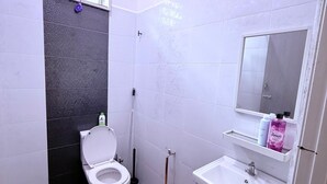 A small bathroom with a toilet, sink, and mirror. - Homestay Selesa KKT Guesthouse (Kuala Terengganu)