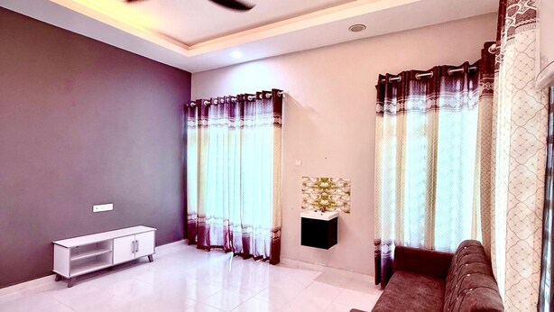 A spacious living room with a ceiling fan, a white entertainment unit, a brown sofa, and patterned curtains. - Homestay Selesa KKT Guesthouse (Kuala Terengganu)