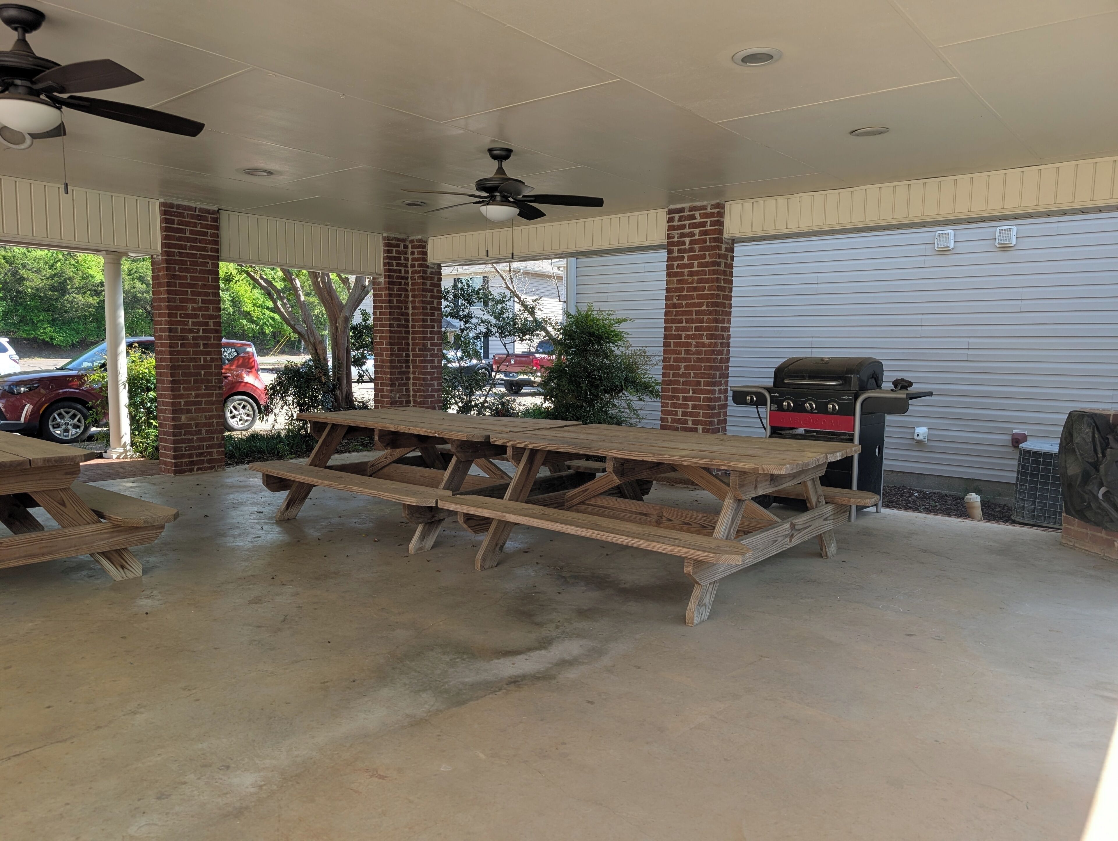 Un espace extérieur abrité avec des tables de pique-nique, un barbecue et une porte de garage.