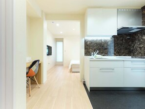 A modern kitchen with white cabinets, a black countertop, and a stainless steel range hood.