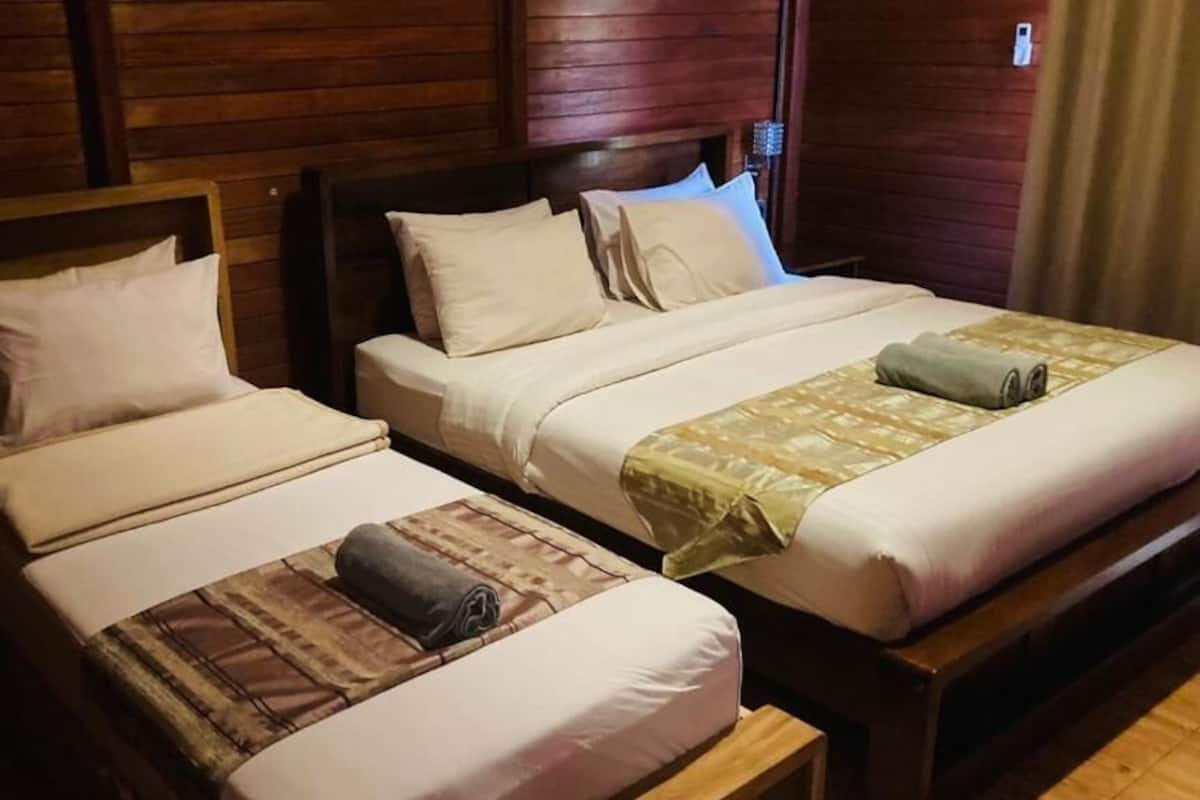 Dos camas individuales con cabeceras de madera y ropa blanca.