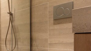 A modern bathroom with a glass shower enclosure, a white toilet, and a wall-mounted control panel. - Charming Modern Studio With AC - Le Marais (Paris)