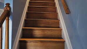 Eine Holztreppe mit Handlauf, die zu einer Tür oben führt.