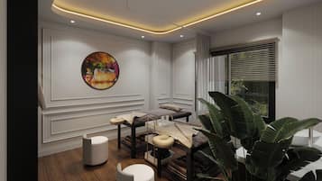 A modern spa room with a wooden floor, a massage table, a large plant, and a wall-mounted artwork.