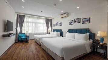 A hotel room with two beds, a TV, a desk, a chair, and a window with curtains.