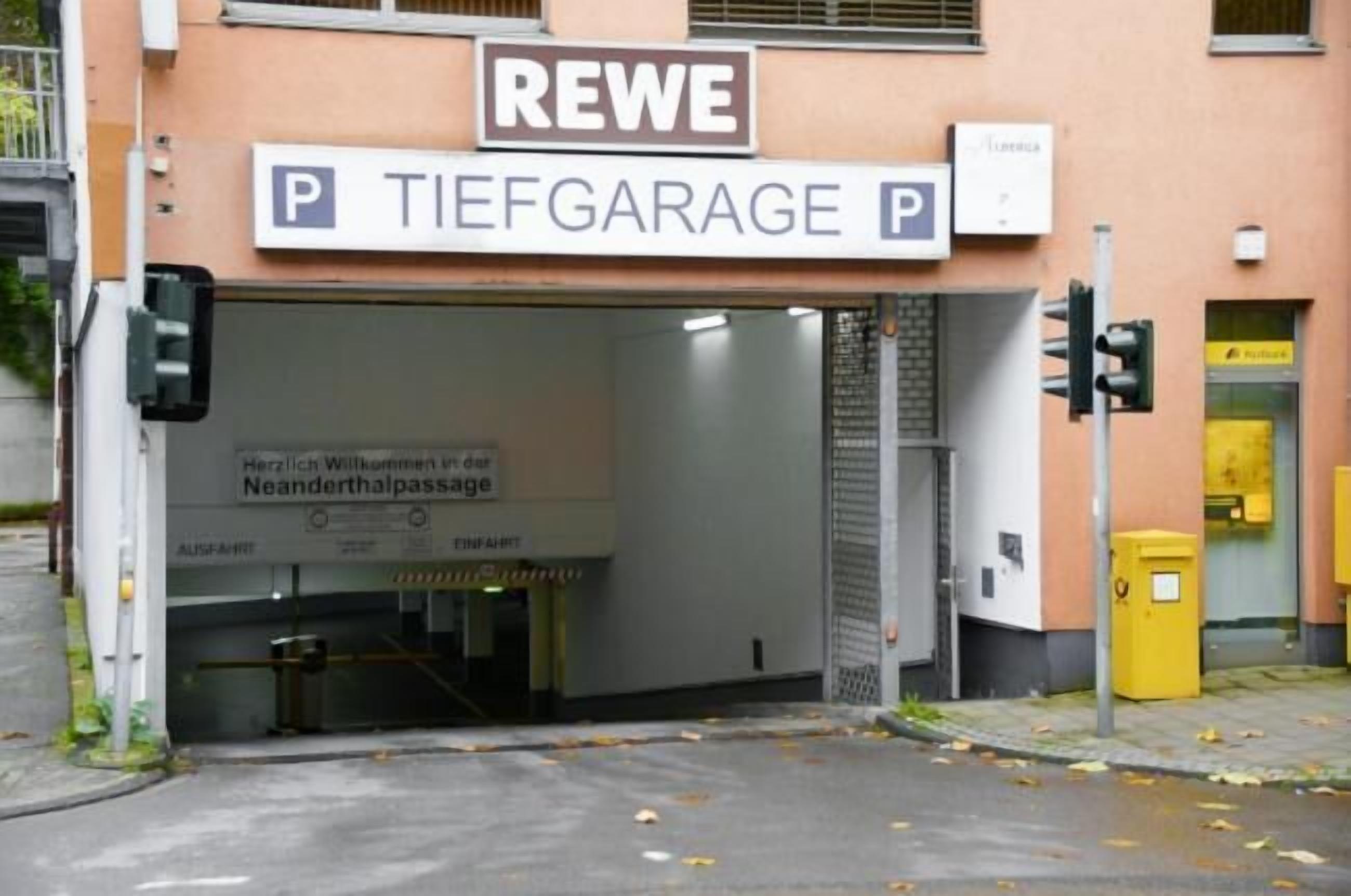 Une entrée de parking avec un panneau indiquant « REWE TIEFGARAGE » et un panneau indiquant un passage piéton.