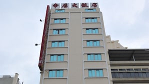 A multi-story hotel with a prominent sign at the top and a large entrance with a brown facade. - Queen Hotel (Kaohsiung)