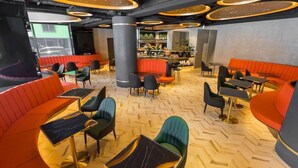 A modern interior with orange seating, black and green chairs, and a herringbone wooden floor. - Queen Hotel (Kaohsiung)
