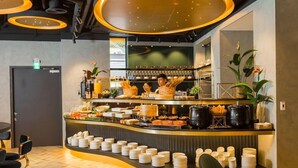 A buffet area with a curved counter, plates, and various food items. - Queen Hotel (Kaohsiung)