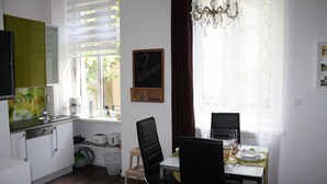 A modern kitchen with a dining area, a chalkboard with 'Welcome' written on it, and a chandelier. - Govienna Small Modern Apartment (Vienna)