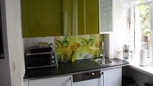 A kitchen with a microwave, sink, and a window with a view of greenery outside. - Govienna Small Modern Apartment (Vienna)