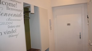 A hotel room with a white door, a small shelf, and a wall-mounted telephone. - Govienna Small Modern Apartment (Vienna)