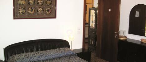 Un dormitorio con cama, un adorno en la pared, una puerta y un aparador.
