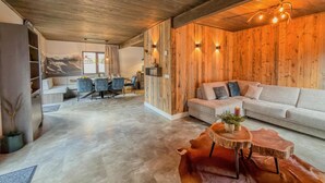 A modern interior with a wooden ceiling, a dining area with chairs and a table, a sofa, and a round wooden table with a leather rug. - Chalet with terrace and sauna on an Alpine lake (Afritz am See)