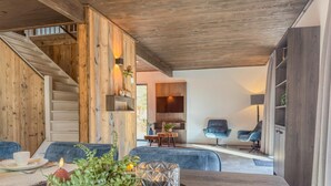 A modern interior with a wooden staircase, a dining area with a table set for two, and a seating area with two chairs. - Chalet with terrace and sauna on an Alpine lake (Afritz am See)