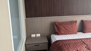 A modern hotel room with a large bed, a nightstand, a window, and a wall-mounted air conditioning unit. - Sitara Hotel Patong Beach (Patong)