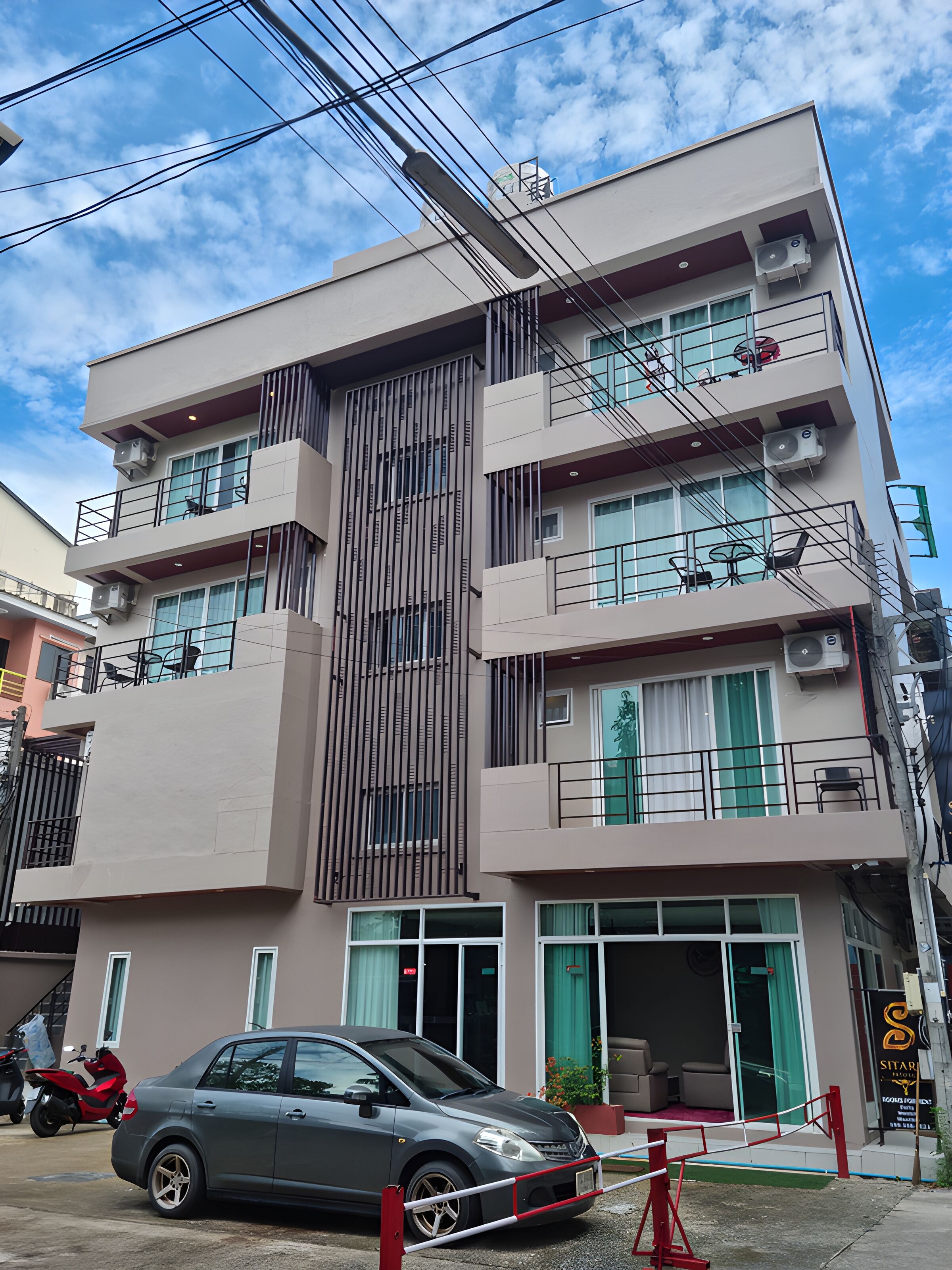 Un immeuble à plusieurs étages doté de balcons, de climatiseurs et d’une entrée sécurisée par un portail.