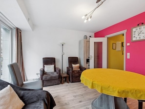 A modern living room with two armchairs, a sofa, a yellow table, and a bright pink wall. - Cosy apartment near the center (Blankenberge)