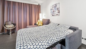 Ein Hotelzimmer mit einem Bett, einem Sessel, einem Schreibtisch und einer Wandlampe.
