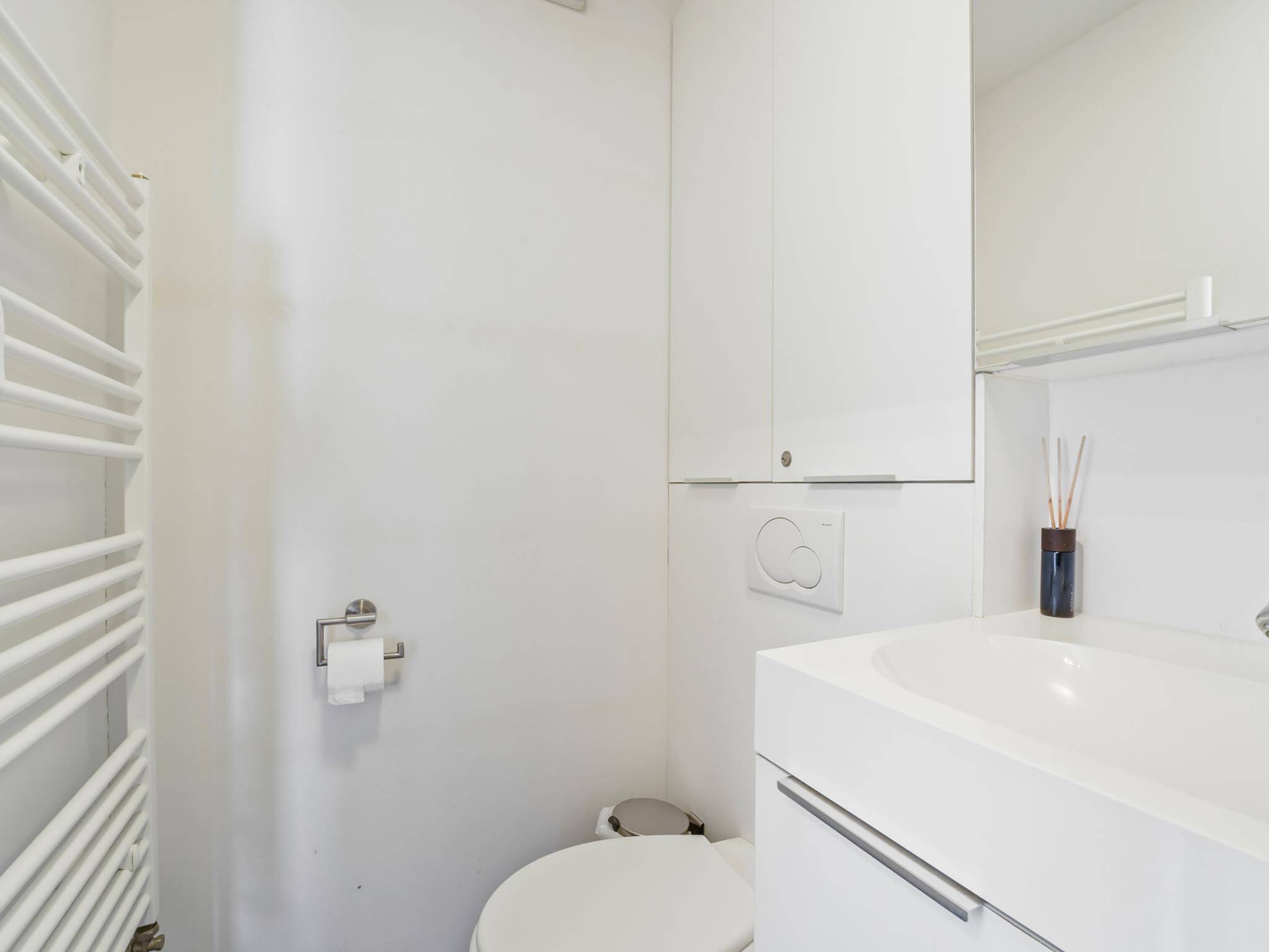 A white bathroom with a toilet, a sink, and a mirror.