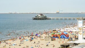 Ein Strand mit einem Steg, einem Rettungsturm und einer großen aufblasbaren Spielkonstruktion.
