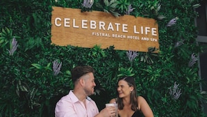 A couple sitting at a table with a sign in the background that reads "CELEBRATE LIFE FISTRAL BEACH HOTEL AND SPA". - Fistral Beach Hotel And Spa Adults Only (Newquay)
