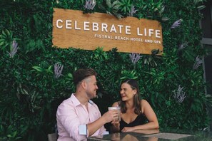 A couple sitting at a table with a sign in the background that reads "CELEBRATE LIFE FISTRAL BEACH HOTEL AND SPA". - Fistral Beach Hotel And Spa Adults Only (Newquay)