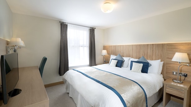 A hotel room with a large bed, two bedside tables, a desk, and a chair. - Fistral Beach Hotel And Spa Adults Only (Newquay)