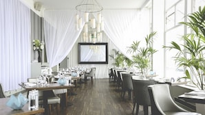 A restaurant with wooden flooring, white curtains, and multiple tables set for dining. - Fistral Beach Hotel And Spa Adults Only (Newquay)