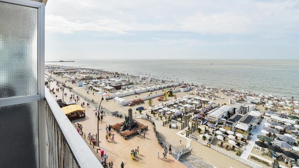 Une vue sur la plage avec une promenade, des parasols et une statue.