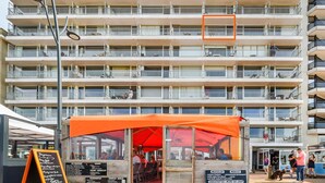 Un hôtel à plusieurs étages, doté de balcons, d’un espace extérieur couvert aménagé en coin salon et d’une enseigne de restaurant bien visible.