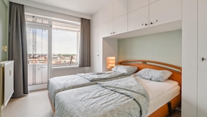 Une chambre moderne avec un grand lit, une table de chevet et une fenêtre avec des rideaux.