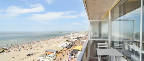Un balcón con vista a una playa y muelle concurridos.