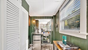 Eine kleine Küche mit einem Edelstahlkühlschrank, einem Spülbecken mit Wasserhahn sowie einer Arbeitsplatte mit Wasserkocher und Kaffeemaschine.
