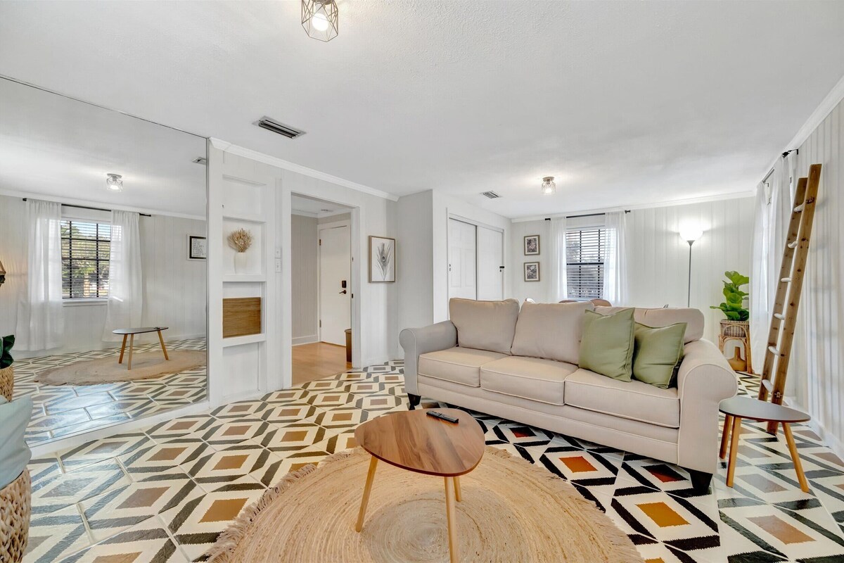Un salon moderne avec un canapé beige, une table basse ronde en bois et un revêtement de sol à motifs.