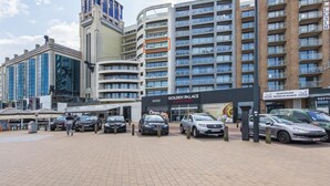 A modern building with multiple floors, a prominent casino sign, and several parked cars in front. - Beautiful apartment by the sea (Blankenberge)