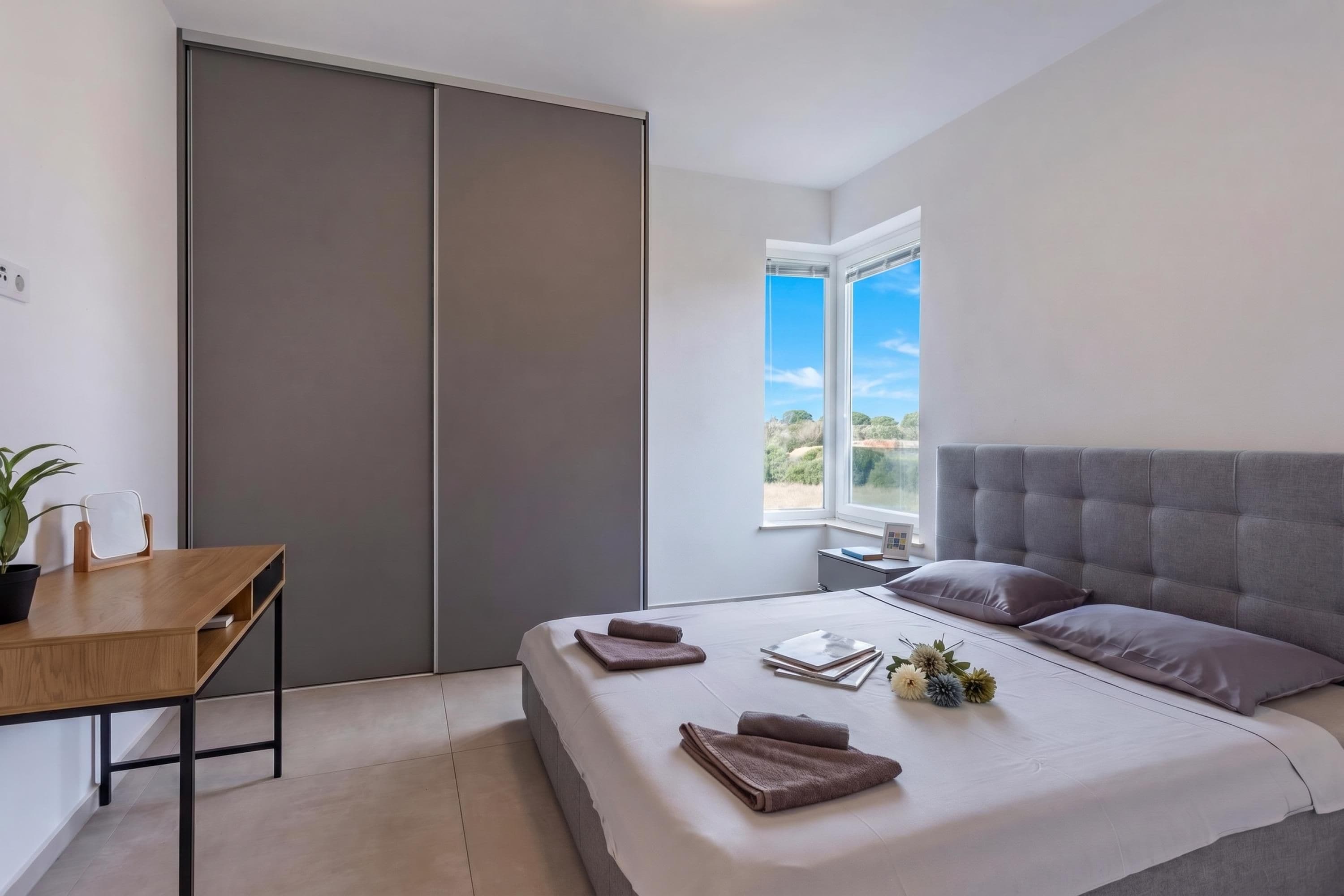Et moderne soveværelse med seng, sengebord og udsigt til det fri.