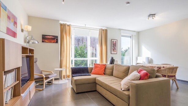 Uma sala de estar moderna com um sofá seccional, uma mesinha, uma estante e uma grande janela com cortinas.