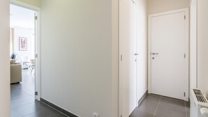 Um corredor com duas portas brancas, um radiador e piso ladrilhado.