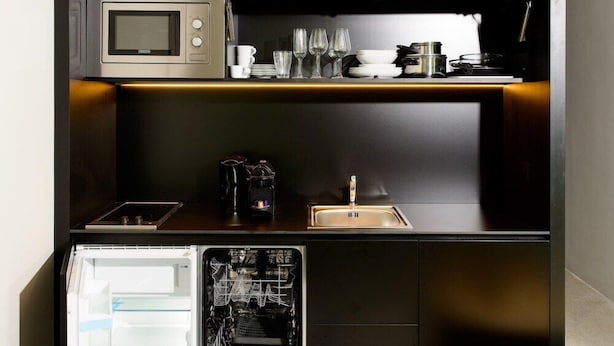 Cocina compacta con microondas integrado, lavaplatos y fregadero.
