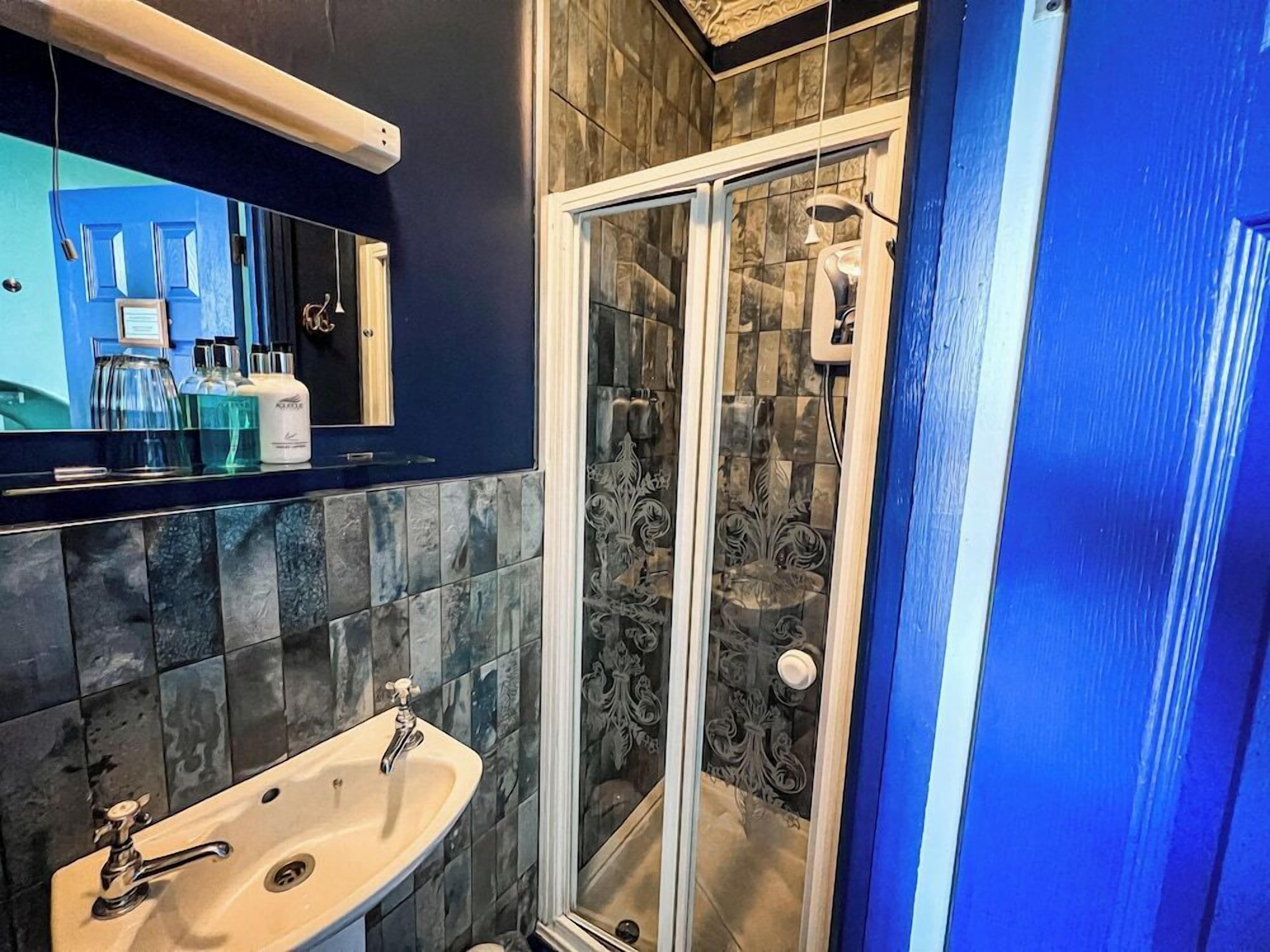 A bathroom with a sink, mirror, and shower area.