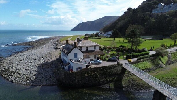 A coastal house with a stone foundation, a thatched roof, and a paved driveway. - Rock House Hotel - Guest House (Lynmouth)