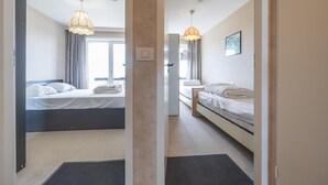 Quarto de hotel com duas camas, uma escrivaninha, uma cadeira e uma janela.
