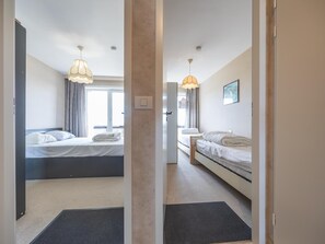 A hotel room with two beds, a desk, a chair, and a window. - Cozy and spacious apartment on the 1st floor (Middelkerke)