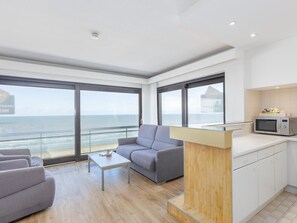 A modern living room with a sofa, a coffee table, and a view of the ocean. - Corner apartment with phenomenal sea view (Middelkerke)