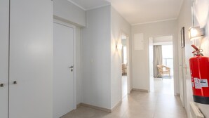 Un pasillo con paredes blancas, un extintor montado en la pared y una puerta al final.