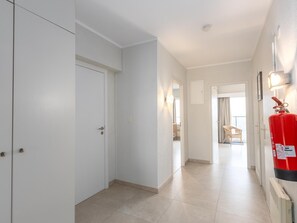 A hallway with white walls, a fire extinguisher mounted on the wall, and a door at the end. - Apartment on the 9th floor with sea view (Middelkerke)