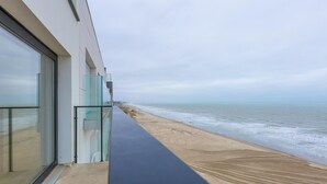 Un edificio moderno con balcón de vidrio que da a la playa.